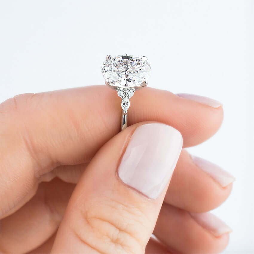 model holding claw set pear shaped lab diamond with marquise and round diamonds on the sides 