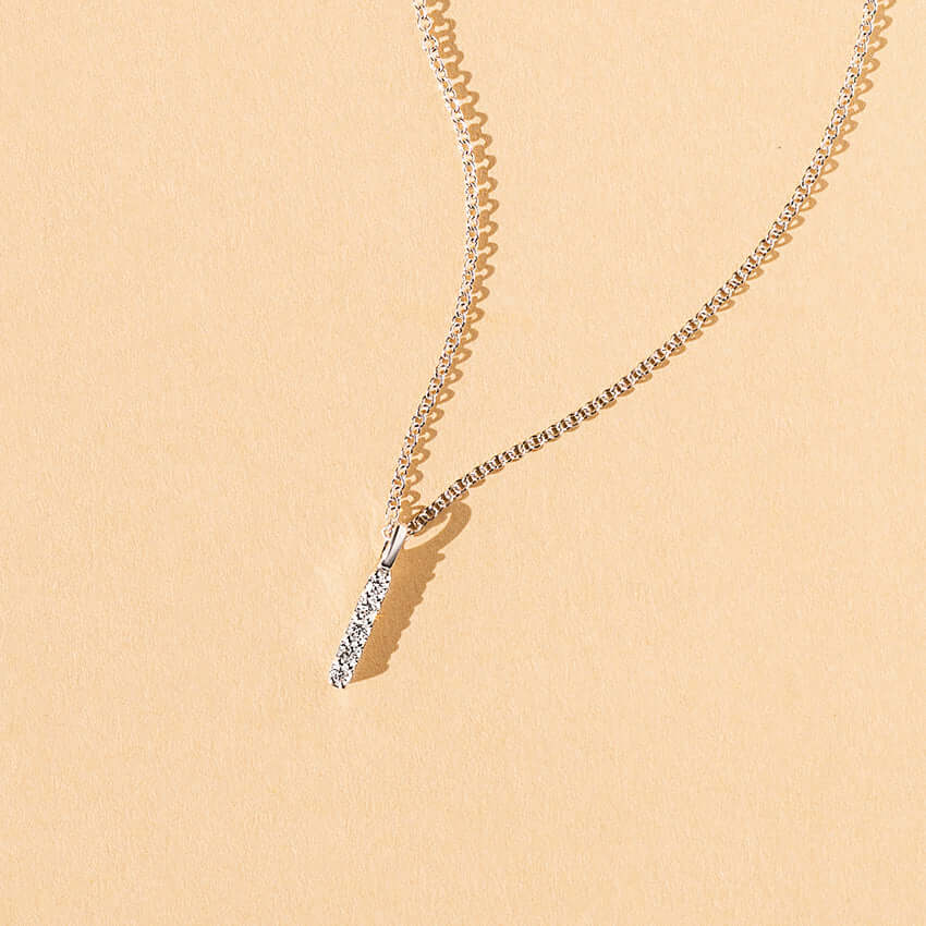 white gold bar pendent with 5 diamonds on background