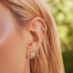 model wearing flower shaped pear and round diamonds yellow gold stud earrings 