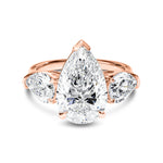 Rose gold ring with pear-shaped diamond on a white background